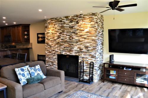 a living room with a brick fireplace with a flat screen tv at Simba Run Vail Condominiums in Vail