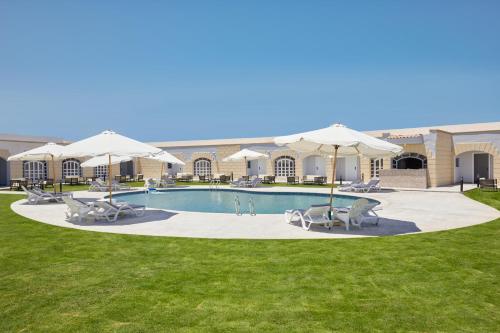 a swimming pool with chairs and umbrellas at Le Royal Marina Hotel in El Alamein