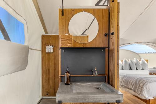 a bathroom with a sink in a room with a bed at Under Canvas West Yellowstone in West Yellowstone