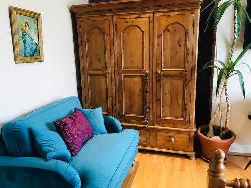 a blue couch in a living room with a wooden cabinet at Stunning Super King, Close to Beach, Shared Bathroom in St. Leonards
