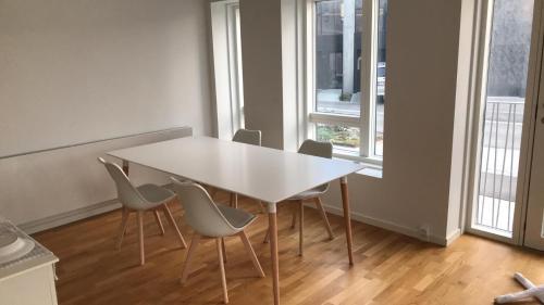 a white table and chairs in a room with windows at Single Room in SHARED APARTMENT with single bed in Copenhagen