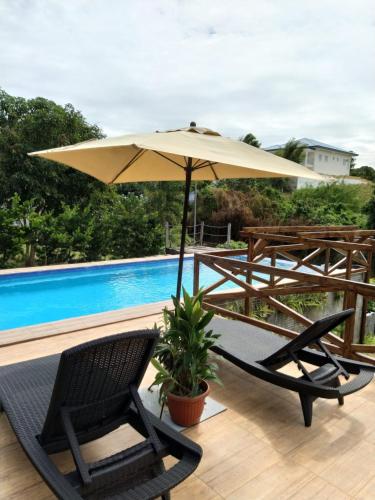 a patio with an umbrella and chairs and a pool at The Boathouse at Calatagan in Sipating