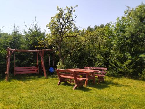a picnic table and benches in a field at Dolistówka Apartamenty, pole namiotowe, balia z jacuzzi, ogród warzywny dla gości, plac zabaw dla dzieci in Goniadz