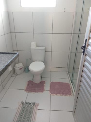 a bathroom with a toilet and two rugs on the floor at Sua casa no litoral in Parnaíba