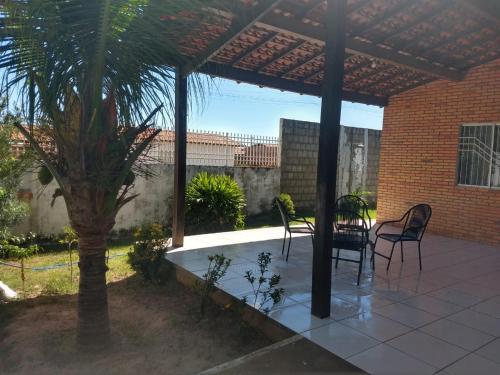 eine Terrasse mit einem Tisch, Stühlen und einer Palme in der Unterkunft Sua casa no litoral in Parnaíba