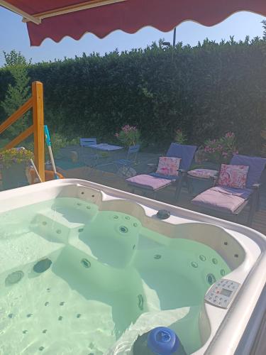 un bain à remous dans une arrière-cour avec des chaises dans l'établissement Chalet & SPA sur la Côte Fleurie, à Auberville