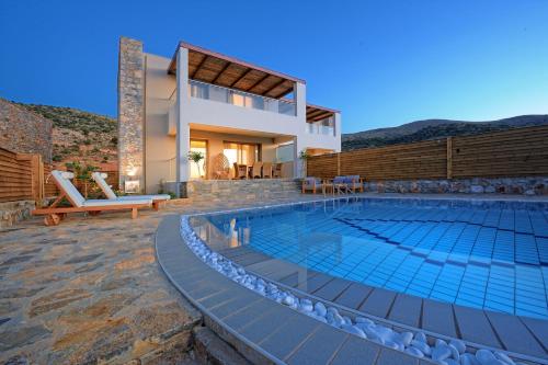 a villa with a swimming pool and a house at Royal Heights Resort Villas & Spa in Malia