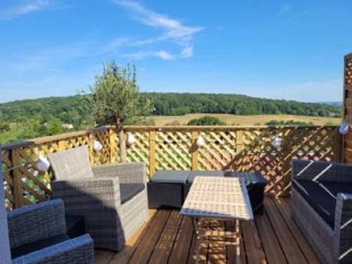 a deck with couches and a table and a view of the countryside at Auberge de la garenne in Saint-Rémy-lʼHonoré