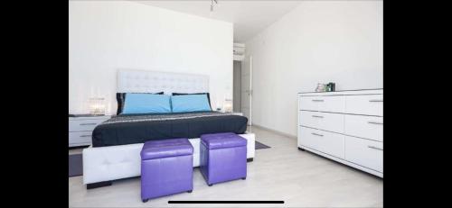 1 dormitorio con 1 cama y 2 taburetes morados en Beach Penthouse Marisol 2Floors, central, en Letojanni