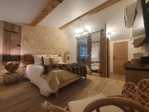 1 dormitorio con 1 cama grande y pared de piedra en La babounette, en Jaujac