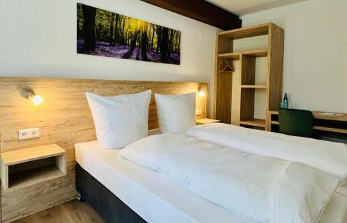 um quarto com uma cama branca e uma secretária em Landhotel Tanneneck - ideal für Gruppen, Familien und Hunde em Löffingen