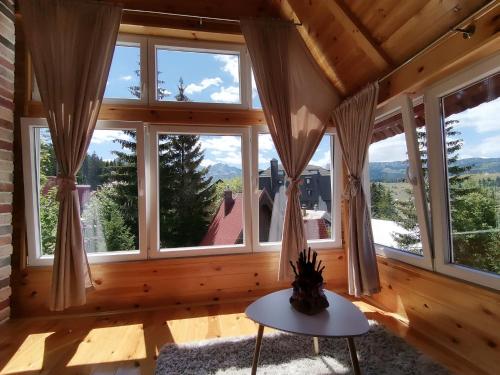 a room with windows and a table with a vase at Guest House Dzakovic Stana in Žabljak