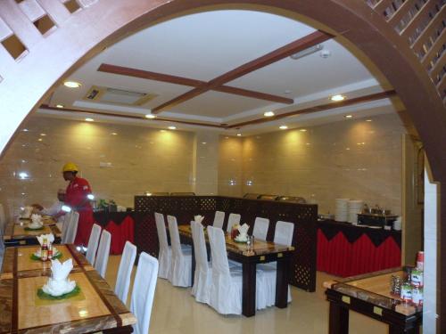 a dining room with tables and white chairs and a person at Nizwa Hotel Apartments in Nizwa