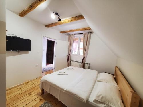 a bedroom with a bed and a flat screen tv at Guest House Dzakovic Stana in Žabljak