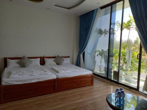 a bedroom with a bed and a table and windows at Tuy Hòa Beach Hotel - Căn hộ du lịch in Tuy Hoa
