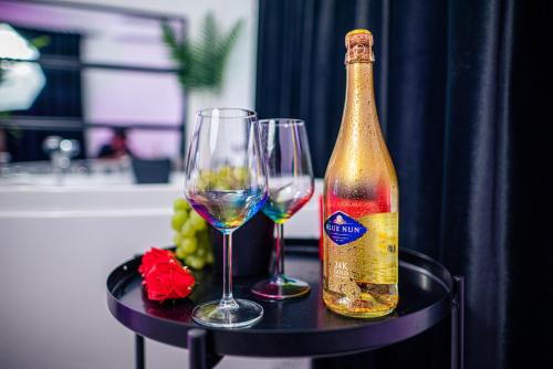 una bottiglia di vino e due bicchieri su un tavolo di Apartment de Lux Craiova Jacuzzi Pat Rotund Semineu Zona Ford a Craiova