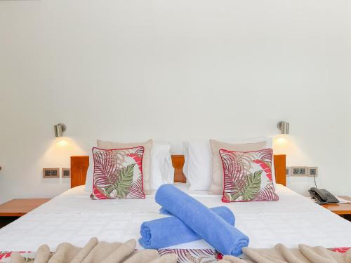 a bedroom with a large bed with two blue pillows at Palm Holiday Apartments in Grand'Anse Praslin