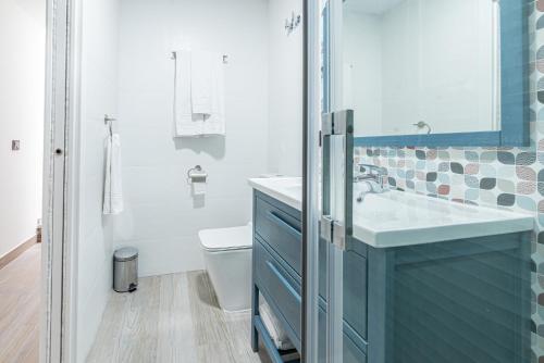 La salle de bains est pourvue d'un lavabo bleu et de toilettes. dans l'établissement Ocean Suites A4, à Isla Cristina