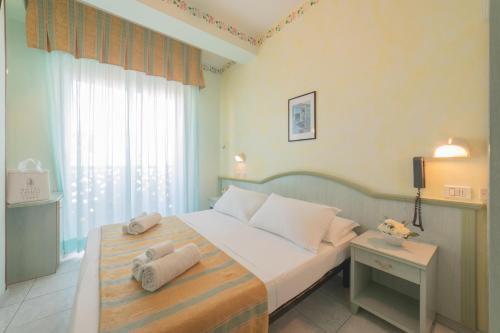 een slaapkamer met een groot bed en handdoeken bij Hotel Cavalli in Cattolica