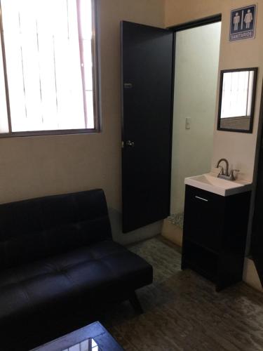 a living room with a black couch and a sink at Trotamundo Oaxaca Hostel in Oaxaca City