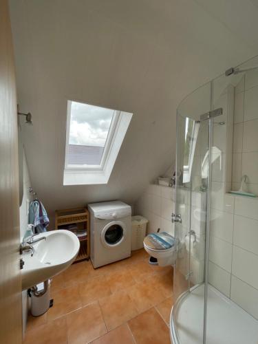 a bathroom with a shower sink and a washing machine at Ferienwohnung Justus in Aurich