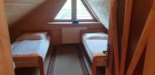 two beds in a small room with a window at Chochołowsko-Witowski Wypoczynek in Witów