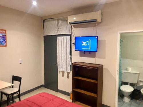 um quarto com uma televisão numa parede com um WC em Granados Hostel em Buenos Aires