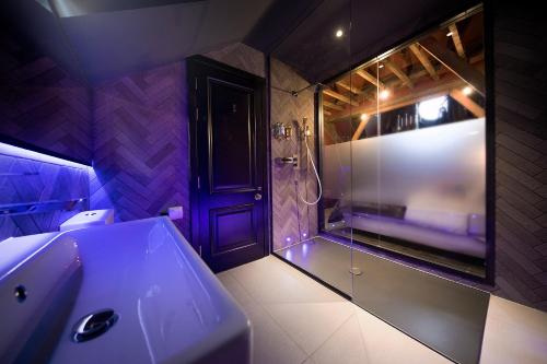 a bathroom with a sink and a shower with purple lighting at The Bells - Luxury Serviced Apartments in Leeds