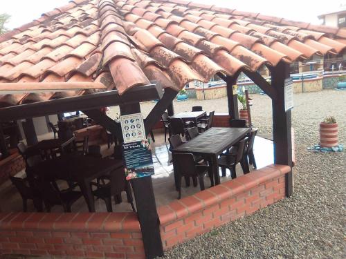 un patio avec une table et des chaises sous un toit dans l'établissement Finca Hotel La Marina, à Quimbaya