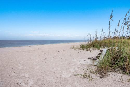 a beach with a bench sitting on the sand at Waters Edge 104S condo in Holmes Beach