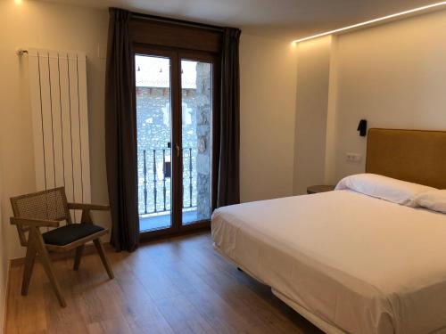 a bedroom with a bed and a chair and a window at HOTEL MONTE PERDIDO in Bielsa
