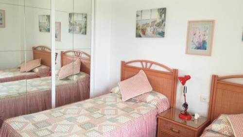 sypialnia z dwoma łóżkami i lustrem w obiekcie HUELVA PLAYAS DEL SUR w mieście El Portil