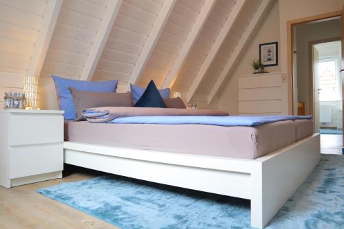 ein Schlafzimmer mit einem großen weißen Bett mit blauen Kissen in der Unterkunft Ferienhaus Poseidon in Dorum Neufeld