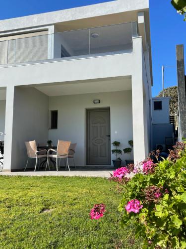 a white house with a patio and a lawn at Elena villa-apartments in Asklipiḯon