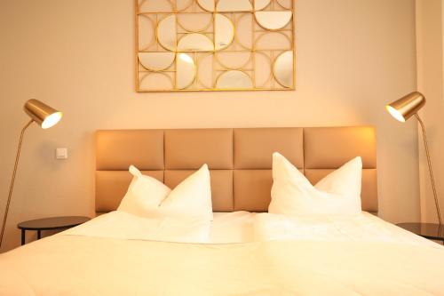 a bed with white pillows and two lamps on it at TM Hotel Düsseldorf in Düsseldorf