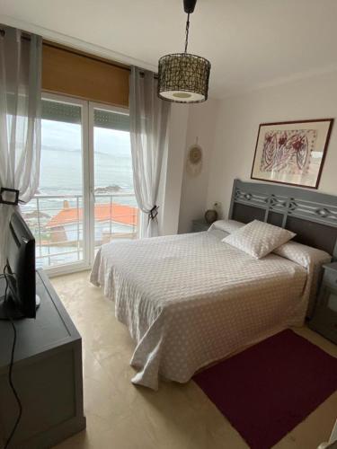 een slaapkamer met een bed en uitzicht op de oceaan bij precioso apartamento con vistas al mar in Sanxenxo