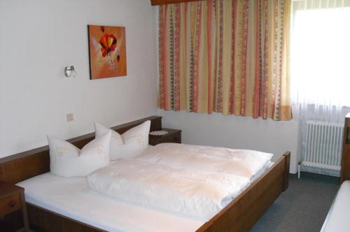 Schlafzimmer mit einem Bett mit weißer Bettwäsche und einem Fenster in der Unterkunft Ferienwohnung Reinstadler in Jerzens