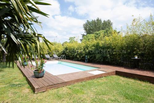 a swimming pool in a yard with a wooden deck at La Galerie in Toulouse