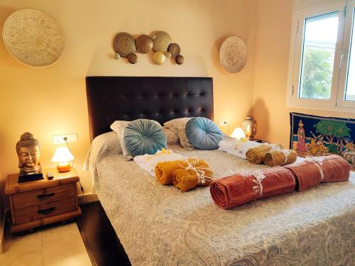 um quarto com uma cama com almofadas em Indo Loma Sancti Petri em Chiclana de la Frontera