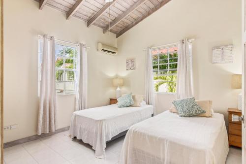 two beds in a room with two windows at Palm View 4 in Watts Village
