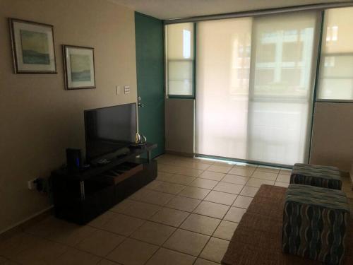 uma sala de estar com uma televisão de ecrã plano e um sofá em AQUATIKA BEACH APT 1ST FL em Loiza