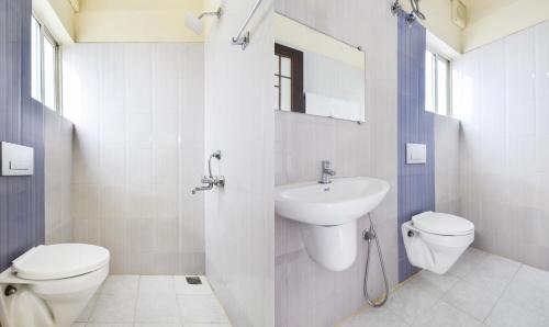 a white bathroom with a toilet and a sink at Itsy Hotels Platinum Inn in Chacka