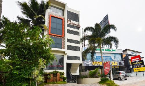 a white building with an orange window and palm trees at Itsy Hotels Platinum Inn in Chacka