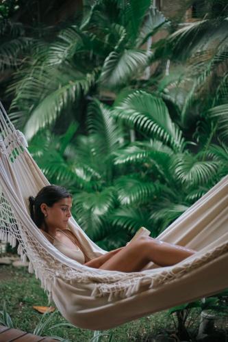 a woman sitting in a hammock in a garden at El Hábita CASA MAR in Santa Teresa Beach