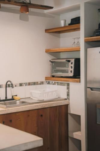 a kitchen with a sink and a microwave at El Hábita CASA MAR in Santa Teresa Beach