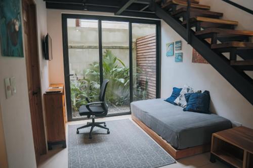 a bedroom with a bed and a chair and a staircase at El Hábita CASA MAR in Santa Teresa Beach