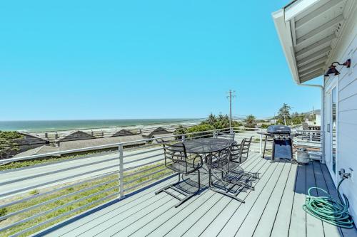 a deck with tables and chairs and the beach at Porters Paradise in Gold Beach