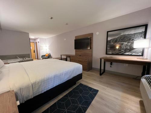 a hotel room with a bed and a desk and a television at Super 8 by Wyndham Cornwall ON in Cornwall