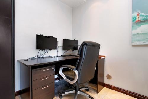 a computer desk with two monitors and a chair at Luxury Beachfront 706 with AC, Workspace & Table Mountain Views in Cape Town