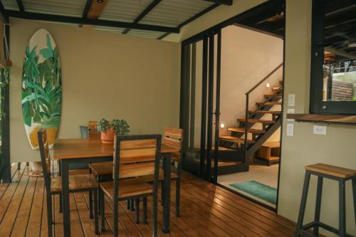 a dining room with a table and chairs and a surfboard on the wall at El Hábita CASA SELVA in Santa Teresa Beach